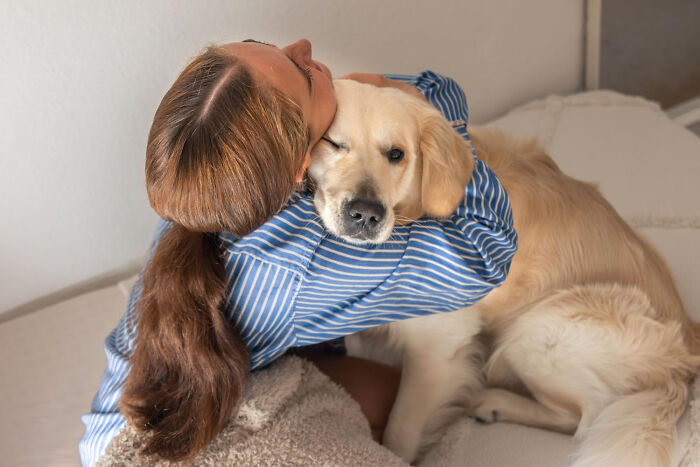 A person hugging a golden retriever, illustrating the importance of companionship amidst societal problems.