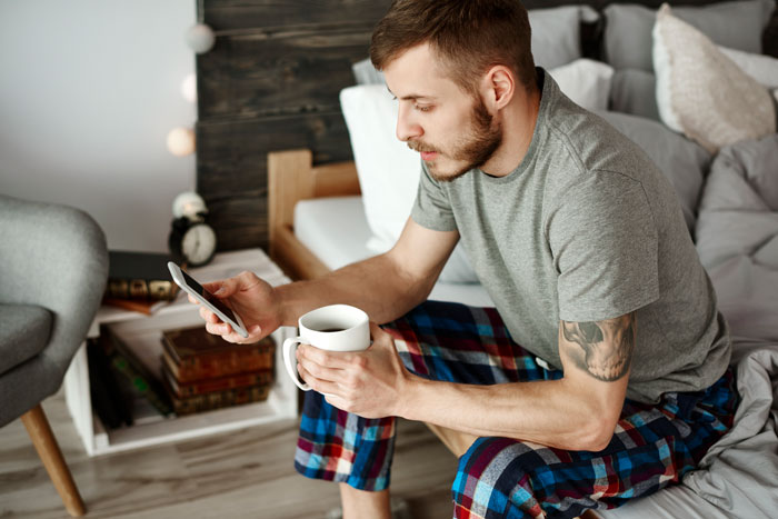 A man in pajamas looking at his phone, illustrating a brother who learned about his sister's liver donation A man in pajamas looking at his phone, illustrating a brother who learned about his sister's liver donation