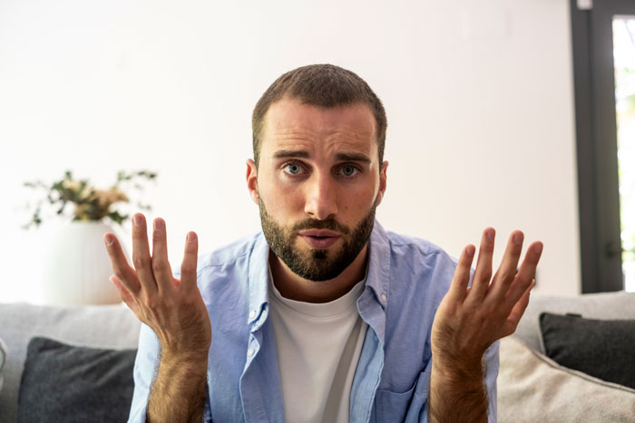Frustrated man shrugging hands on couch representing a dad who learns family is not a free babysitting service. Frustrated man shrugging hands on couch representing a dad who learns family is not a free babysitting service.