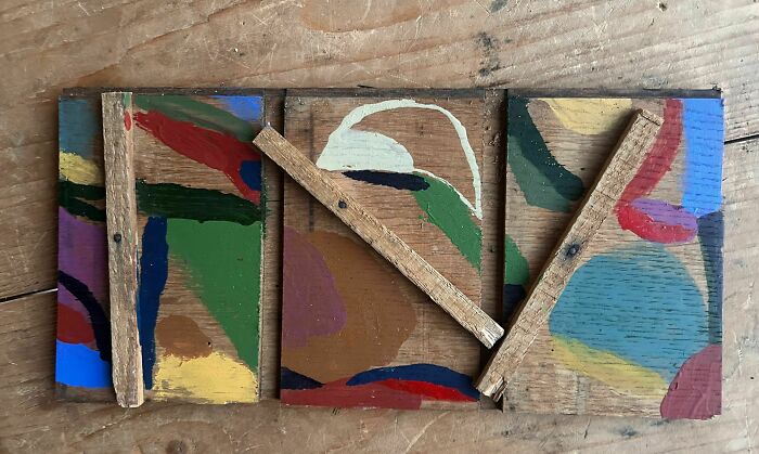 Three rectangular wooden blocks with abstract creative art by Heather Chontos in various colors, joined by wooden sticks.