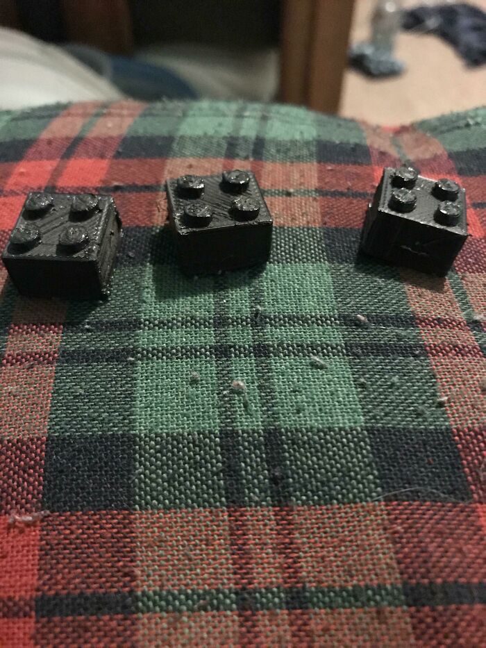 Three small, black, square-shaped objects, similar to Lego bricks, created using 3D printers technology.