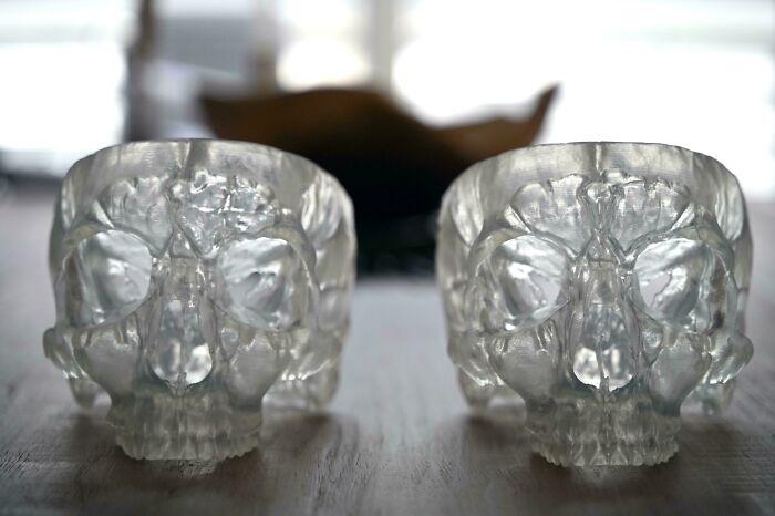 Two translucent skull-shaped candle holders, intricate and clear, showcasing brilliant 3D printers design.