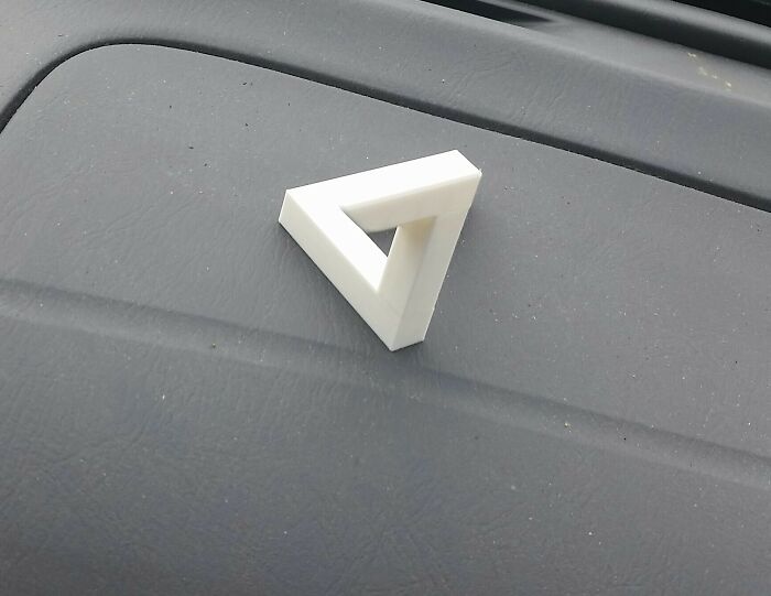 A small, white 3D printed Penrose triangle illusion, an example of brilliant stuff made with 3D printers.