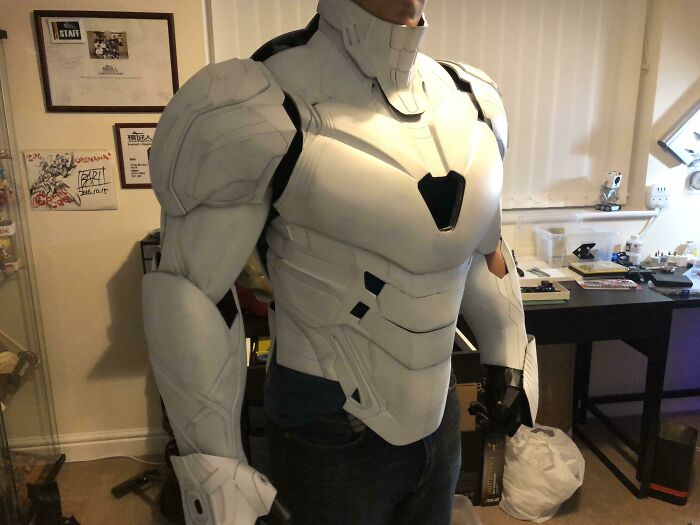 A person wearing a futuristic white and black suit of armor, brilliant stuff created with 3D printers.