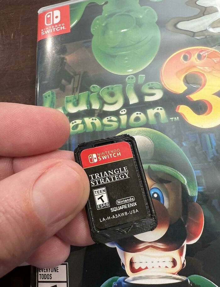 A hand holding a tiny 3D printed Nintendo Switch game cartridge, an example of brilliant stuff made with 3D printers.