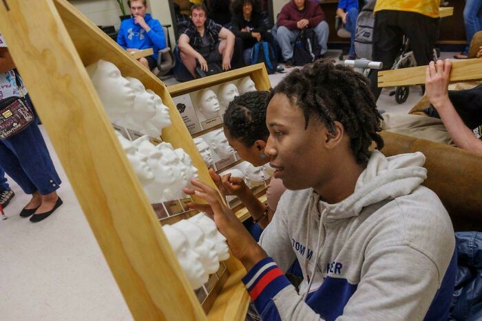 A young man examining a display of 3D printed masks, showcasing brilliant stuff created with 3D printers.