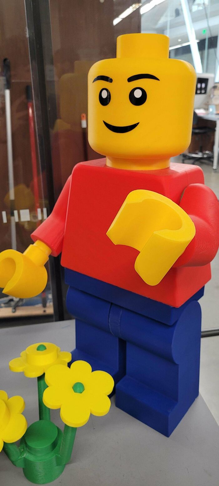 A large, colorful LEGO figure with yellow flowers, showcasing a brilliant use of 3D printers.