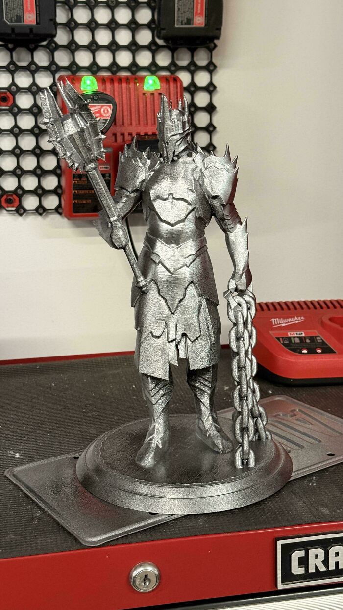 A detailed silver warrior figurine holding a weapon and chains, an excellent example of brilliant 3D printers creations.