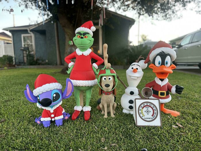 Various Christmas characters including Grinch and Stitch, brilliant creations from 3D printers, on a lawn.
