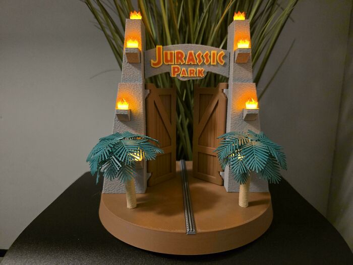 A miniature, illuminated Jurassic Park gate model with palm trees, brilliant stuff made with 3D printers.