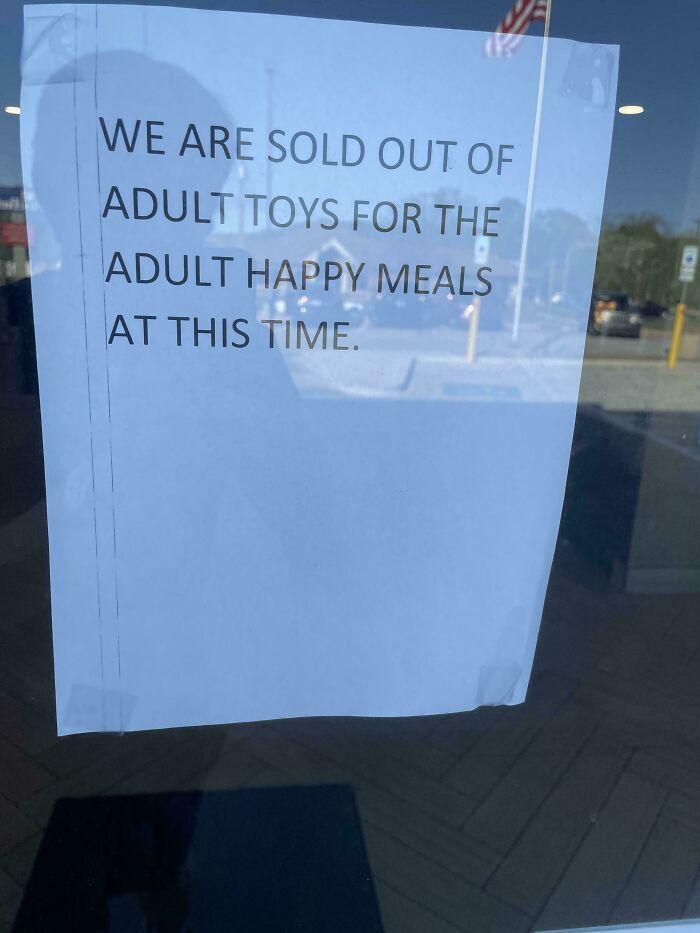 A sign taped to a window stating sold out of adult toys for adult happy meals, a cringy fail.