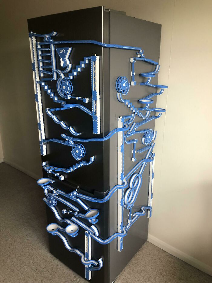 A complex marble run contraption with blue and white tracks, brilliant stuff created using 3D printers on a refrigerator.