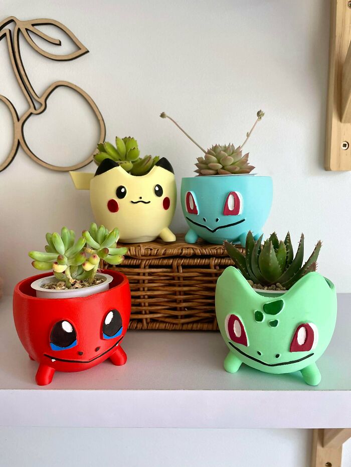 Four colorful 3D printed Pokemon planters with succulents inside, demonstrating brilliant stuff.
