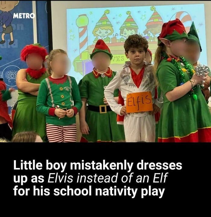 A little boy dressed as Elvis with 'Elfvis' sign, surrounded by children in elf costumes for a school nativity play, creating comedy.