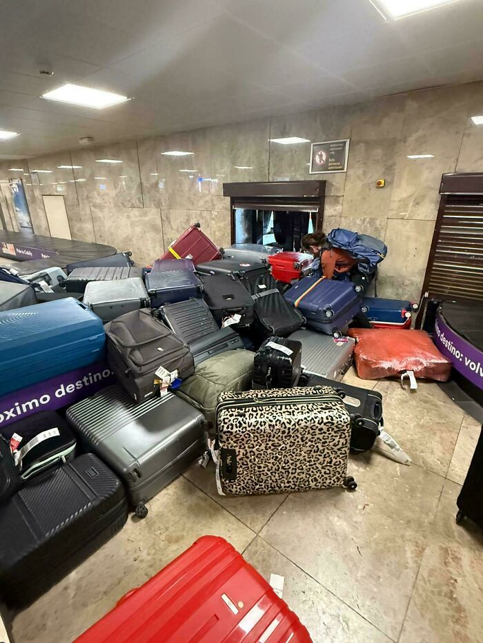 A huge pile of scattered luggage blocking a doorway at the airport, a hilarious and weird thing spotted.
