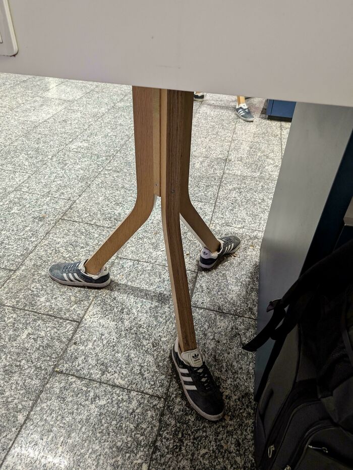 Wooden table legs fitted with shoes, resembling a person's legs, a hilarious and weird thing spotted at airports.