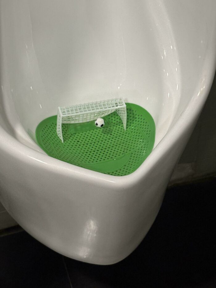 A miniature soccer goal and ball inside a urinal at the airport, one of the hilarious things spotted.