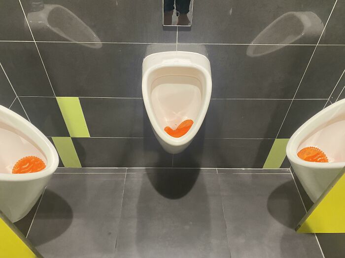Three urinals with orange air fresheners, a funny sight among the weird things spotted at airports.