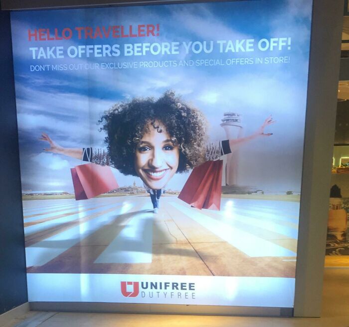A UNIFREE DUTYFREE ad at the airport featuring a smiling woman's face and shopping bags over a runway, a weird thing spotted.