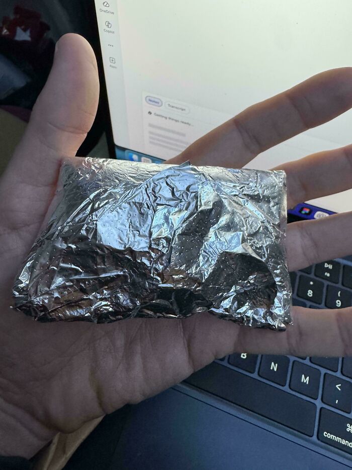 A hand holding a foil-wrapped item at the airport, a weird thing spotted at airports that nobody could have prepared for.