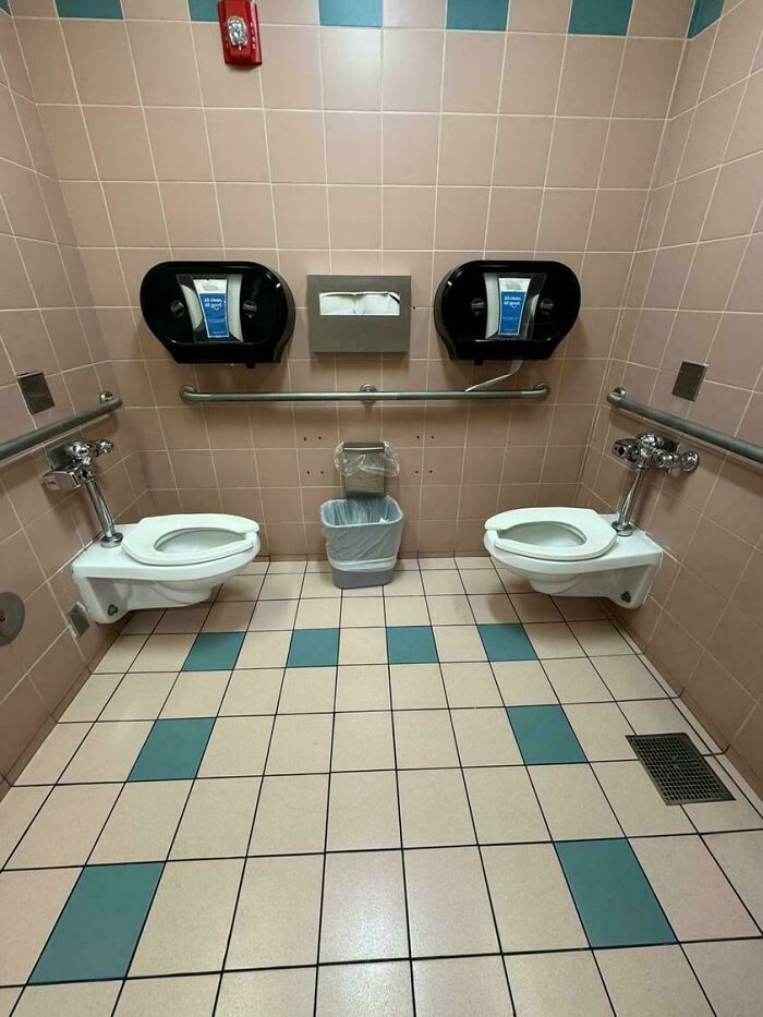 A restroom at the airport with two toilets right next to each other, a weird thing spotted at airports.
