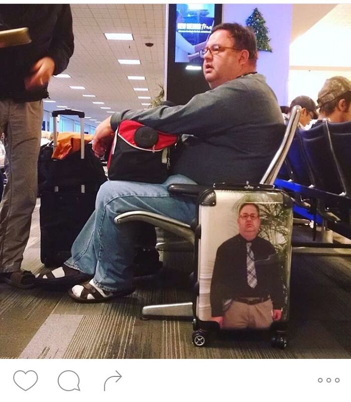 A man sitting at an airport gate, next to a suitcase with his own picture on it, a hilarious thing spotted at airports.