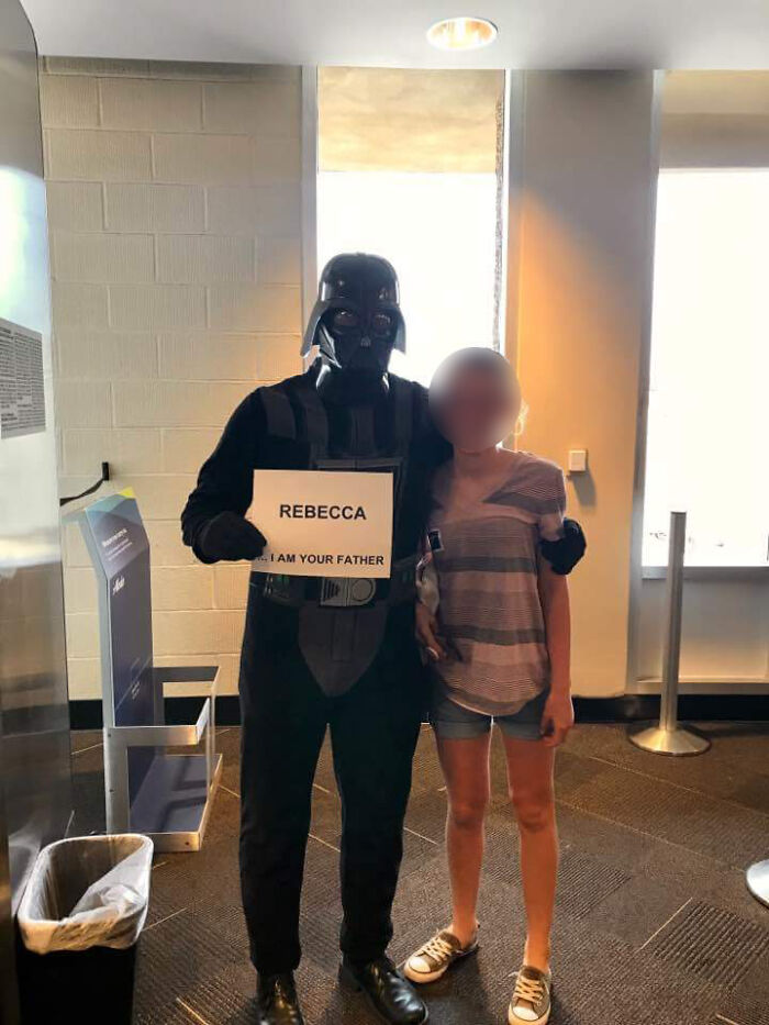 Darth Vader holding a sign saying Rebecca...I am your father next to a woman, a hilarious thing spotted at airports.