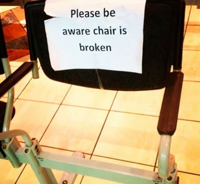A funny sign saying Please be aware chair is broken taped to a broken chair.