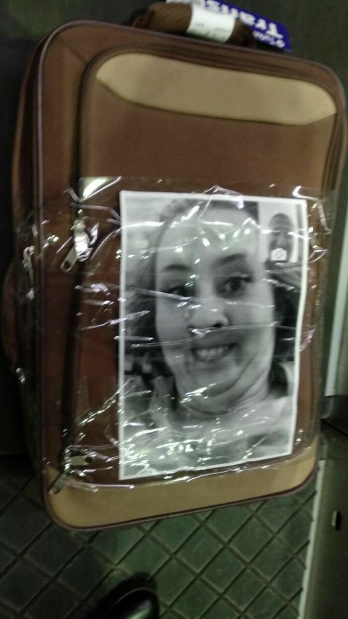 A weird thing spotted at airports: a suitcase with a large photo of a smiling woman taped to it.