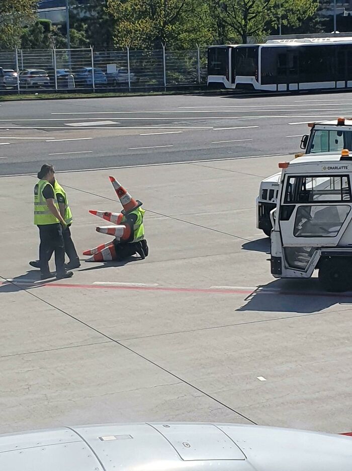 Hilarious airport worker in a traffic cone costume, spotted at airports, creating a weird and funny scene.