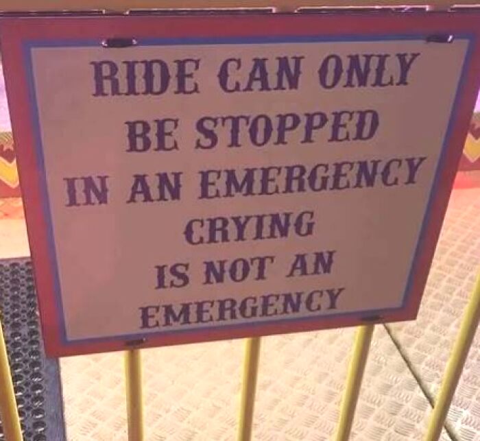A funny sign at a fairground ride stating that crying is not an emergency, emphasizing silly rules.