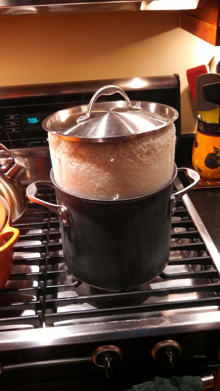 An overflowing pot of rice on a stovetop, demonstrating a humorous kitchen fail.