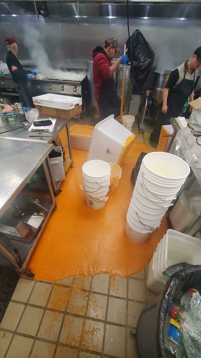 A massive kitchen fail with a restaurant floor covered in spilled orange food, depicting a chaotic and unfortunate kitchen scene.