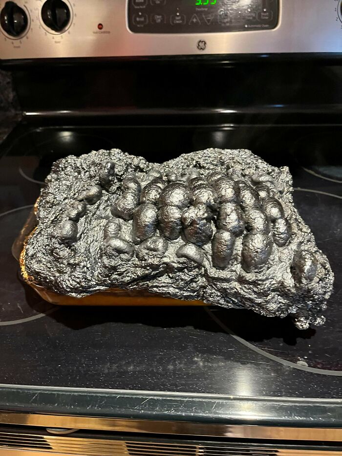 A catastrophic kitchen fail with a burnt, bubbly, unidentifiable food mass on a stovetop, highlighting unfortunate cooking.