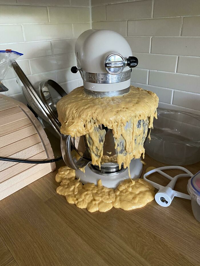 A stand mixer overflowing with dough, creating a sticky kitchen fail on the counter.
