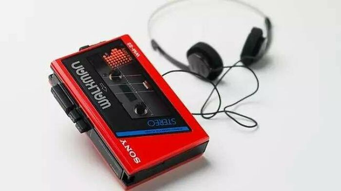 A red Sony Walkman with headphones, an iconic piece of 80s retro tech, on a white surface.
