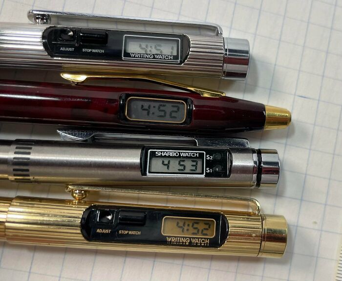 Close-up of four retro tech writing watches from the '80s, showcasing vintage digital time displays and pen designs.