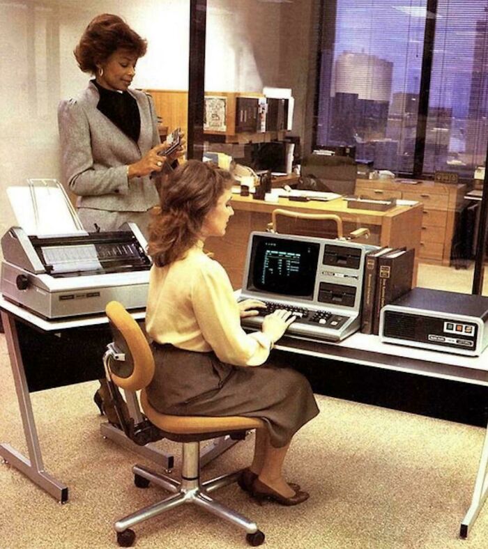 Retro tech photo showing 80s office workers using vintage computers and a printer.