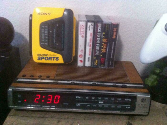 A Sony Walkman, cassette tapes, and a digital clock radio display '80s retro tech items on a bedside table.