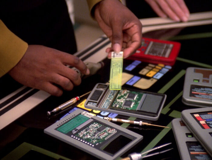 Hands work on a disassembled electronic device with circuit boards, symbolizing retro tech from the '80s.
