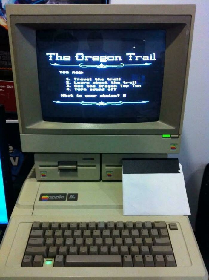 An old Apple II computer displaying The Oregon Trail game, capturing the essence of 80s retro tech.