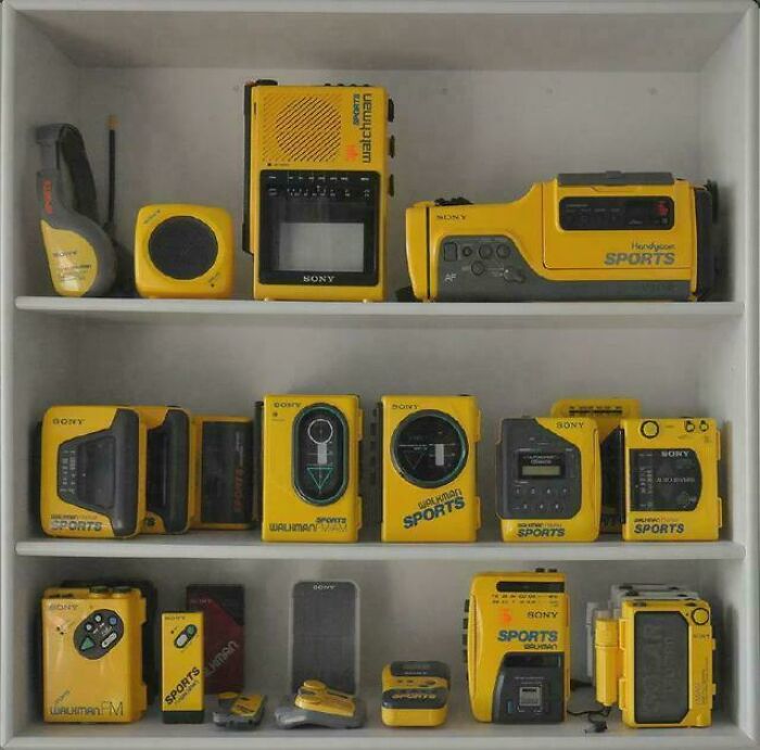 A display of yellow and black Sony retro tech devices, including Walkmans and a Watchman, showcasing 80s technology.