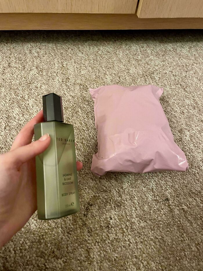 A hand holding a bottle of Ted Baker body spray next to a pink package, an unhinged Vinted post.