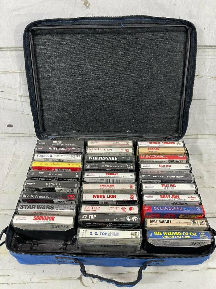 A wide collection of music cassettes stored in a black carrying case, showcasing the variety of 80s retro tech audio.