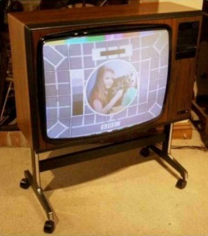 An '80s retro tech television with a test pattern on the screen, showing a girl and a cat.