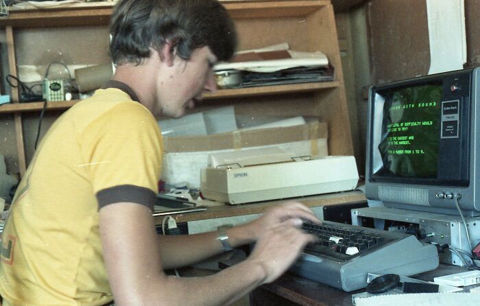 Young man using a retro tech computer with a green screen, a classic image of 80s technology.