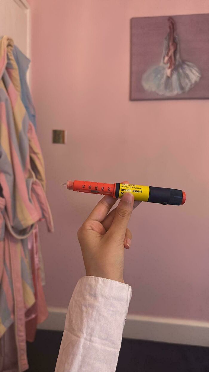 Hand holding an insulin pen in a room with pink walls, one of many unhinged Vinted posts.