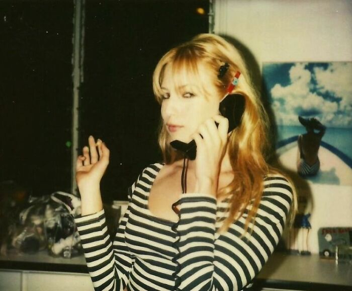 Woman using vintage phone handset with striped top and hair clips