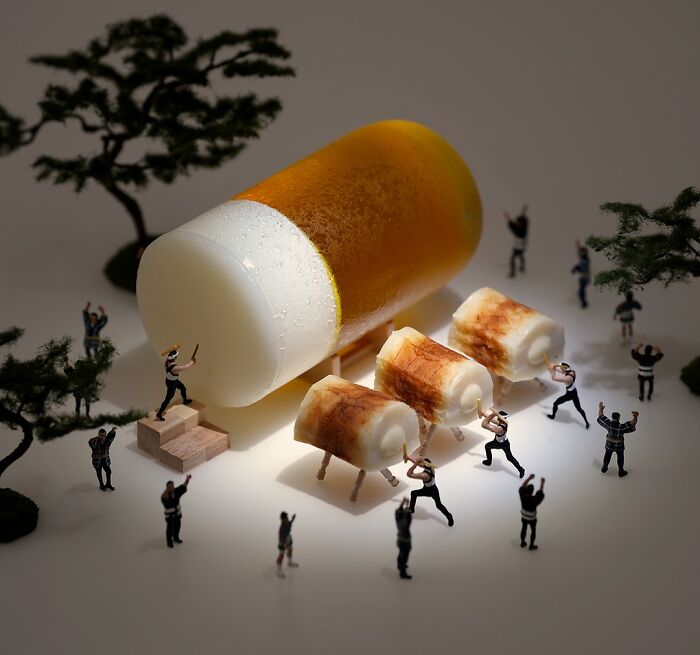 Tatsuya Tanaka miniature calendar work: Tiny figures moving large fish cakes from a fallen roll of processed food.