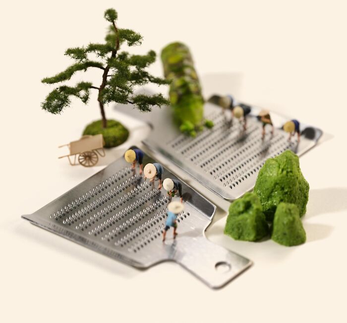 Tatsuya Tanaka's miniature calendar artwork shows tiny figures on cheese graters with green food, a bonsai tree nearby.
